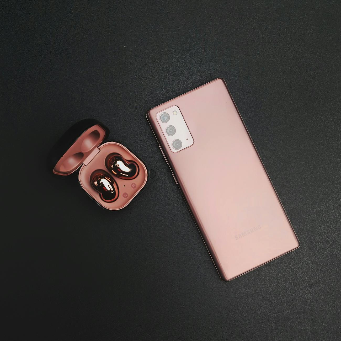 A modern smartphone paired with wireless earbuds on a minimalist black background, showcasing elegance and technology.